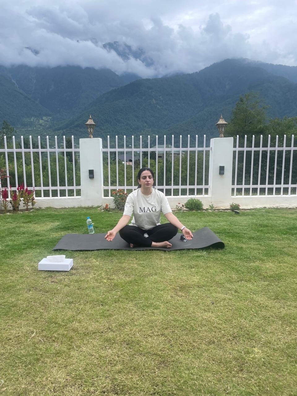 MAG retreat participant meditating outdoors against misty mountains